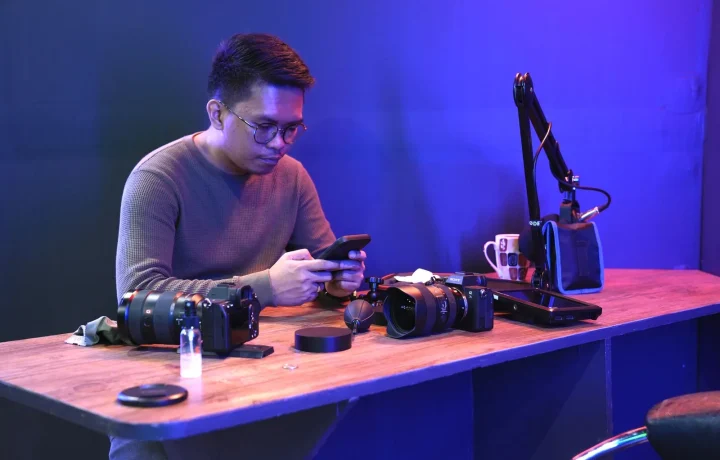 Man at a desk speaking to cameras while reading a script on a smartphone, showing the future of teleprompters in action