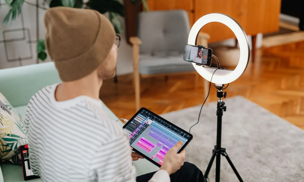 Man recording video content at home with a tablet and ring light, showcasing a teleprompter for vlogging setup