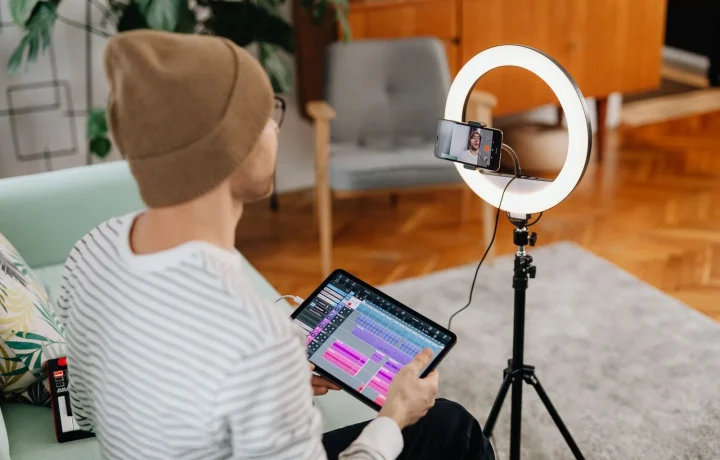 Man recording video content at home with a tablet and ring light, showcasing a teleprompter for vlogging setup