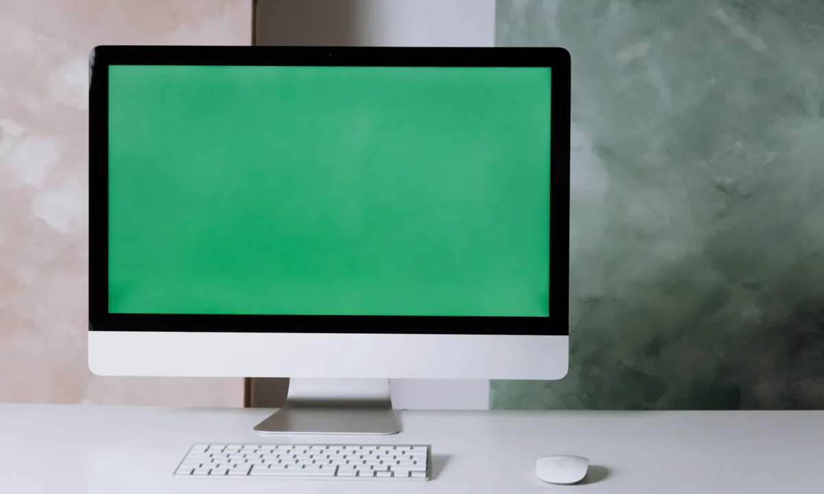 Minimalist workspace with a computer and green screen, illustrating the future of teleprompters technology