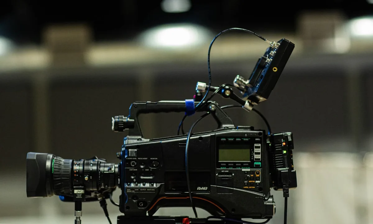 Professional cinema camera with cables and monitor lit by studio lights for a teleprompter for video formats setup