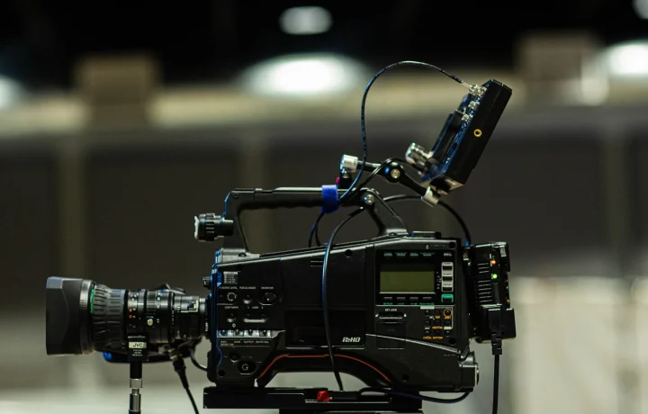Professional cinema camera with cables and monitor lit by studio lights for a teleprompter for video formats setup