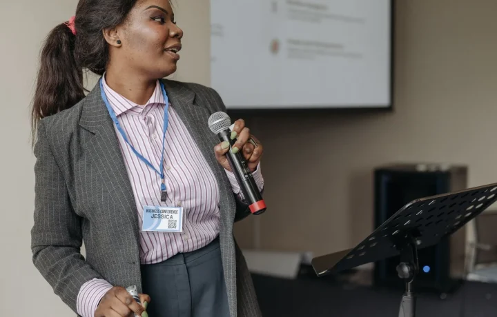 Professional woman presenting at a business seminar, effectively engaging audience with teleprompters