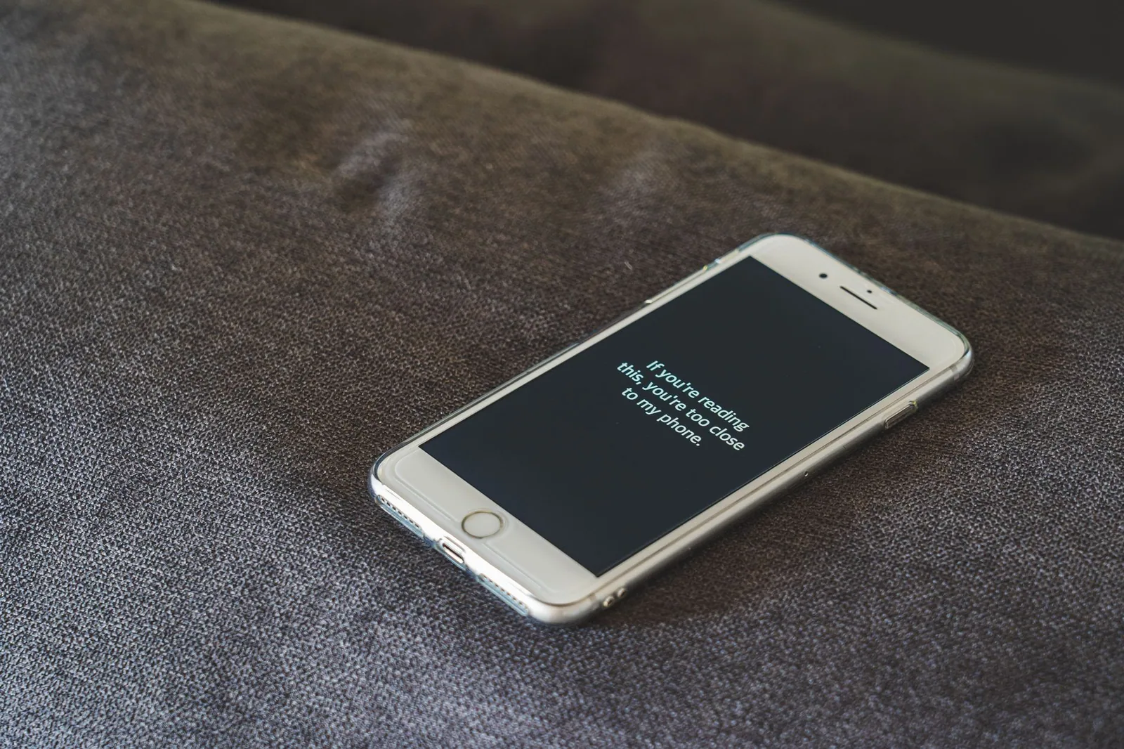Smartphone with a playful lock screen message on a grey couch, highlighting privacy in app features