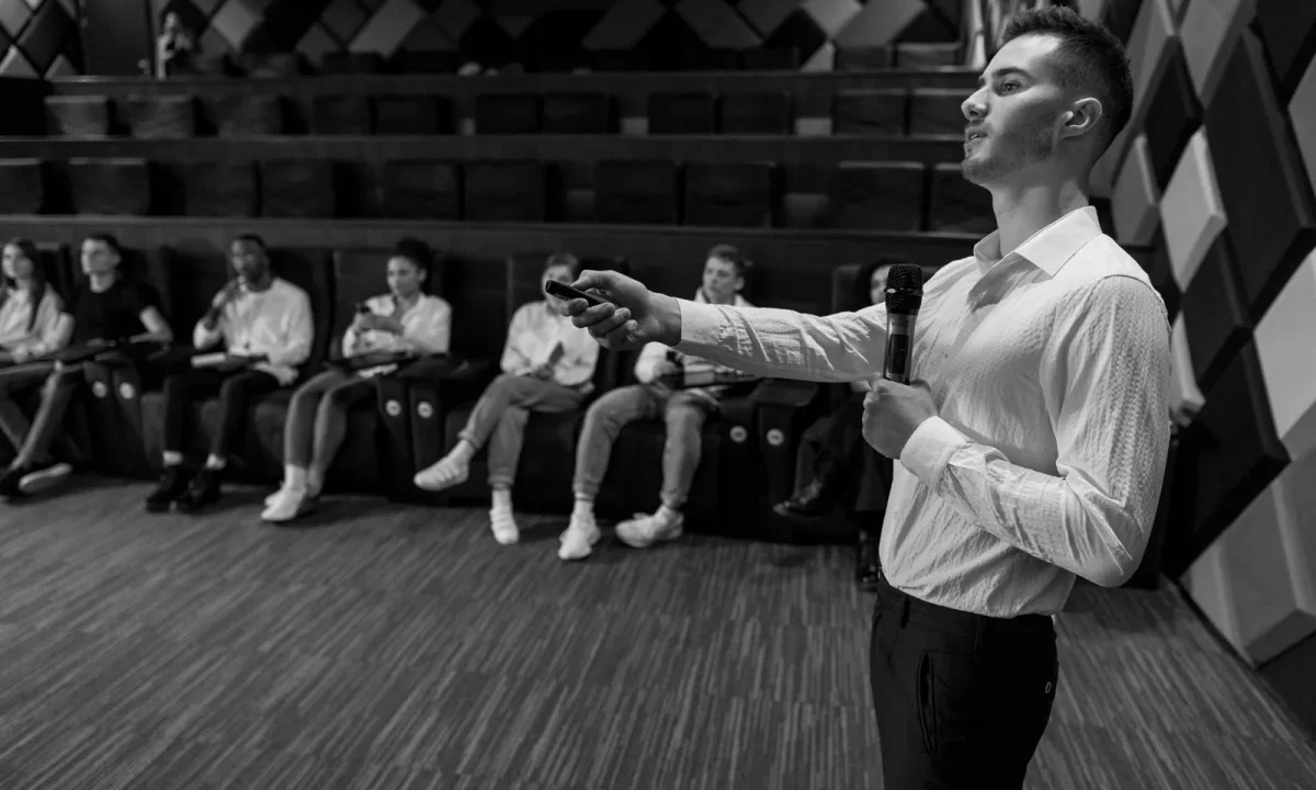 Speaker delivering a presentation in a modern auditorium, highlighting the use of audience engagement teleprompters