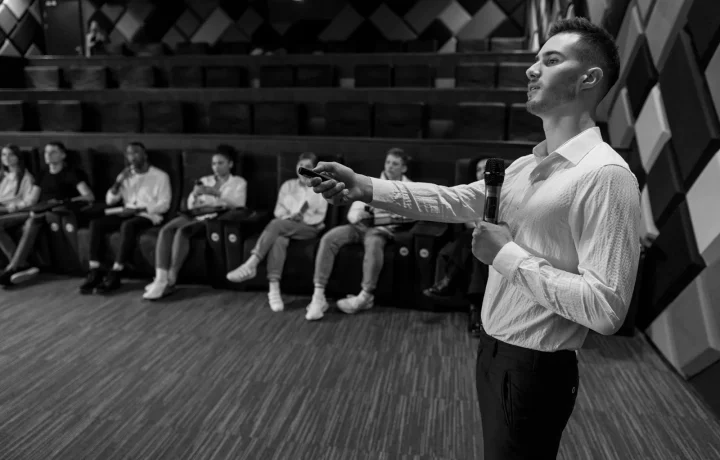 Speaker delivering a presentation in a modern auditorium, highlighting the use of audience engagement teleprompters