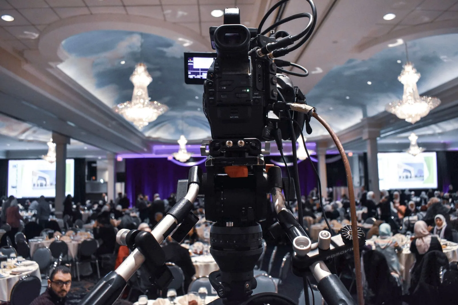 Tripod-mounted video camera filming a crowded ballroom dinner party, a setting that can shake confidence