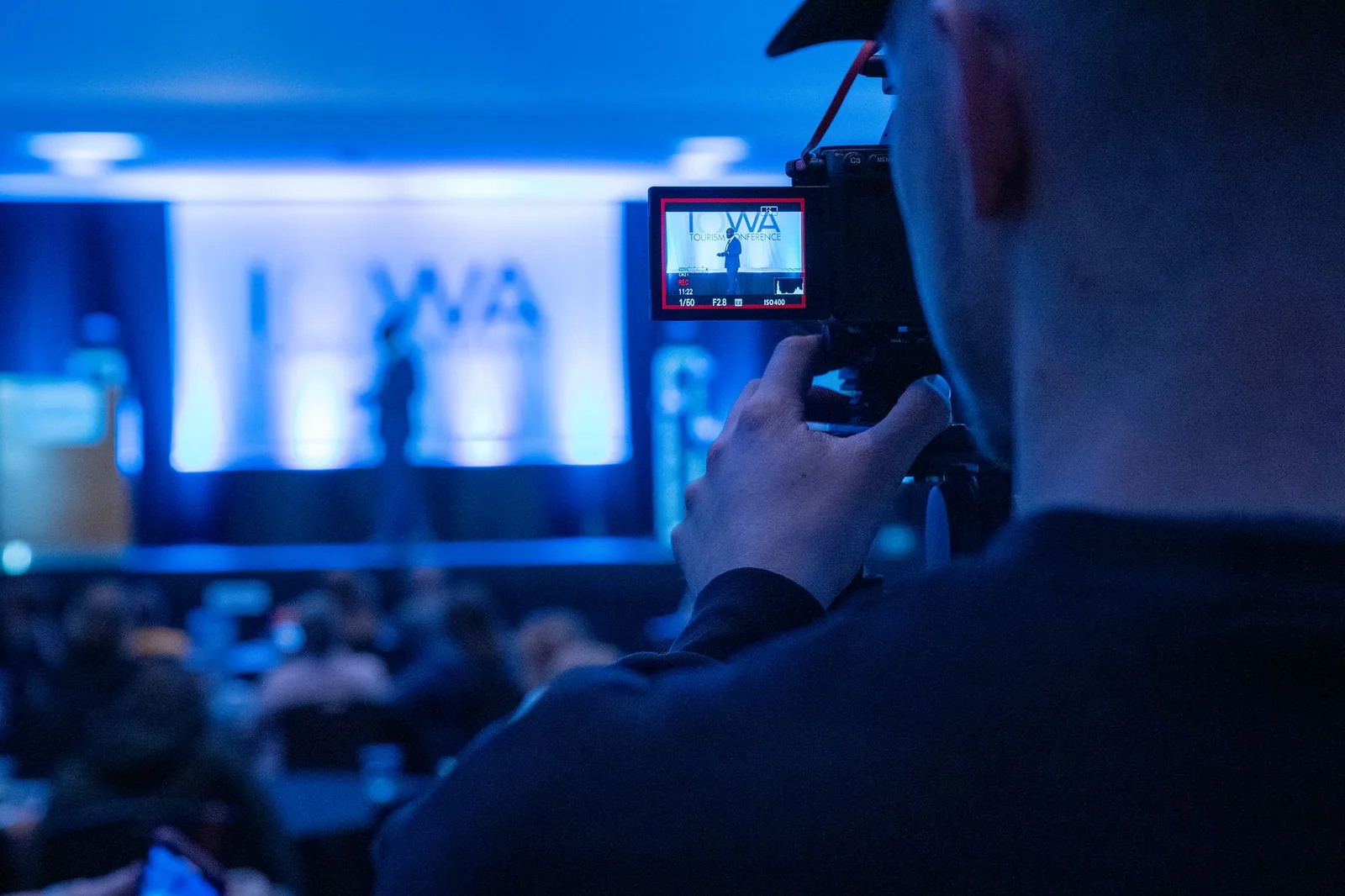 Videographer filming a conference event with professional camera gear for live production
