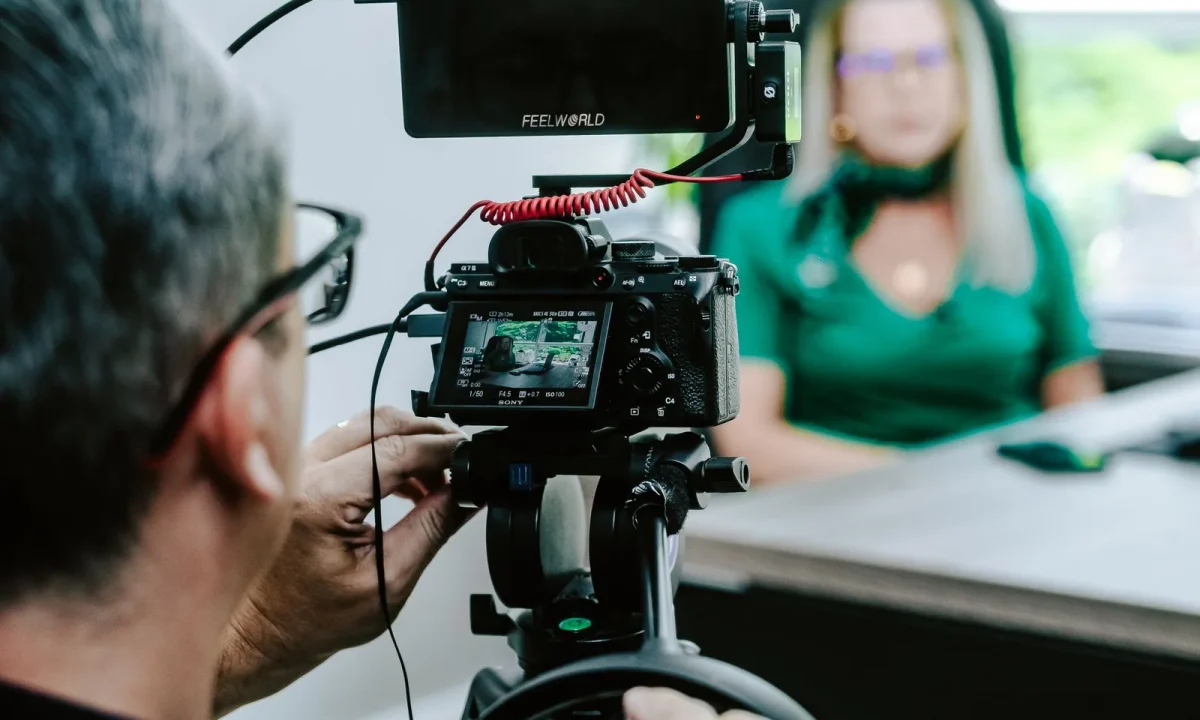 Videographer filming a presenter in an office, a live streaming teleprompter setup for smooth on-camera delivery