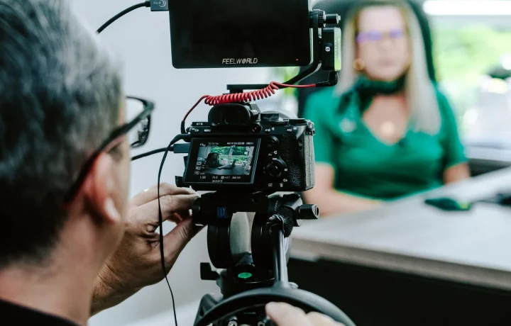 Videographer filming a presenter in an office, a live streaming teleprompter setup for smooth on-camera delivery