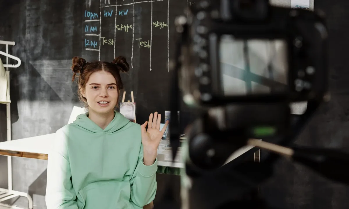 Woman in a mint green hoodie using a live streaming teleprompter from her home studio setup