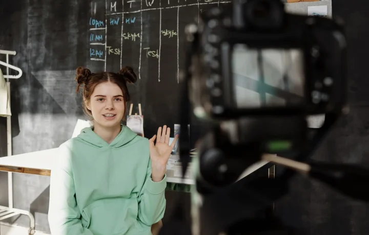 Woman in a mint green hoodie using a live streaming teleprompter from her home studio setup