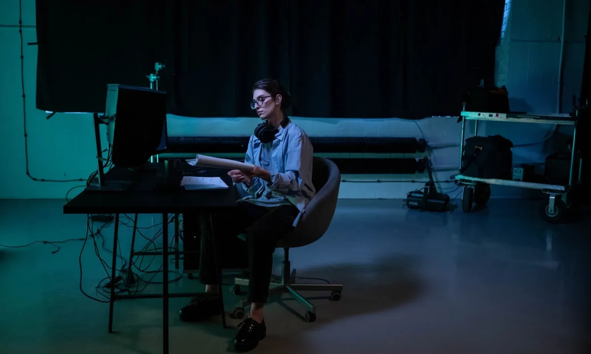 Woman writing a teleprompter script late at night in a moody studio environment