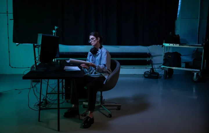 Woman writing a teleprompter script late at night in a moody studio environment