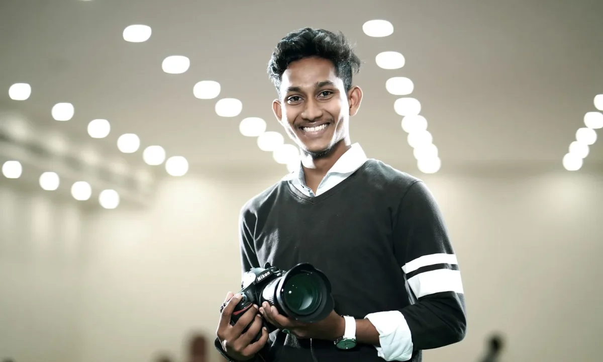 Young man exuding on-camera confidence while holding a camera with modern lights in the background
